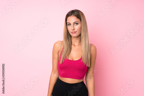 Young sport blonde woman over isolated pink background stretching arm © luismolinero