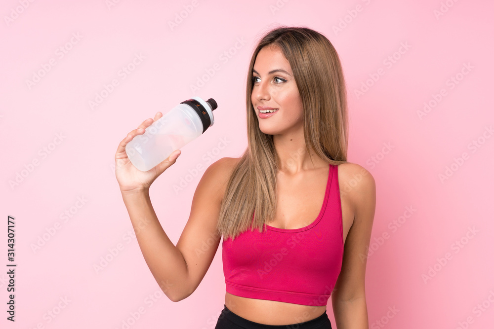 Young sport blonde woman over isolated pink background with sports water bottle Young sport blonde woman over isolated pink background with sports water bottle