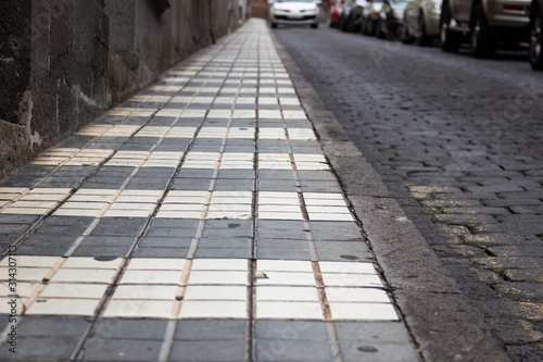 Black and white striped sidewalk street by cobblestone road in Arucas town, Gran Canaria. Empty street, no pedestrians concepts © Josu Ozkaritz