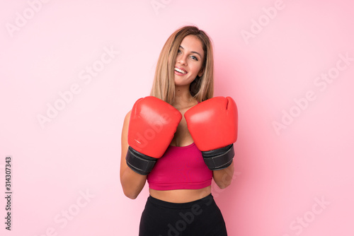 Young sport blonde woman over isolated pink background with boxing gloves © luismolinero