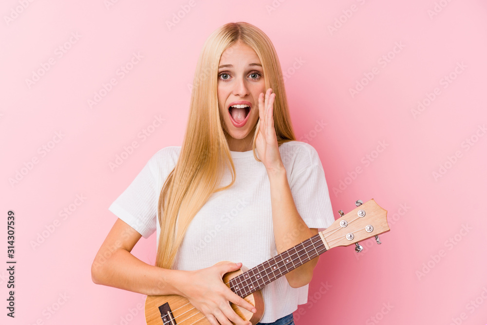 Young blonde girl playing ukelele shouting excited to front. Young blonde girl playing ukelele shouting excited to front.