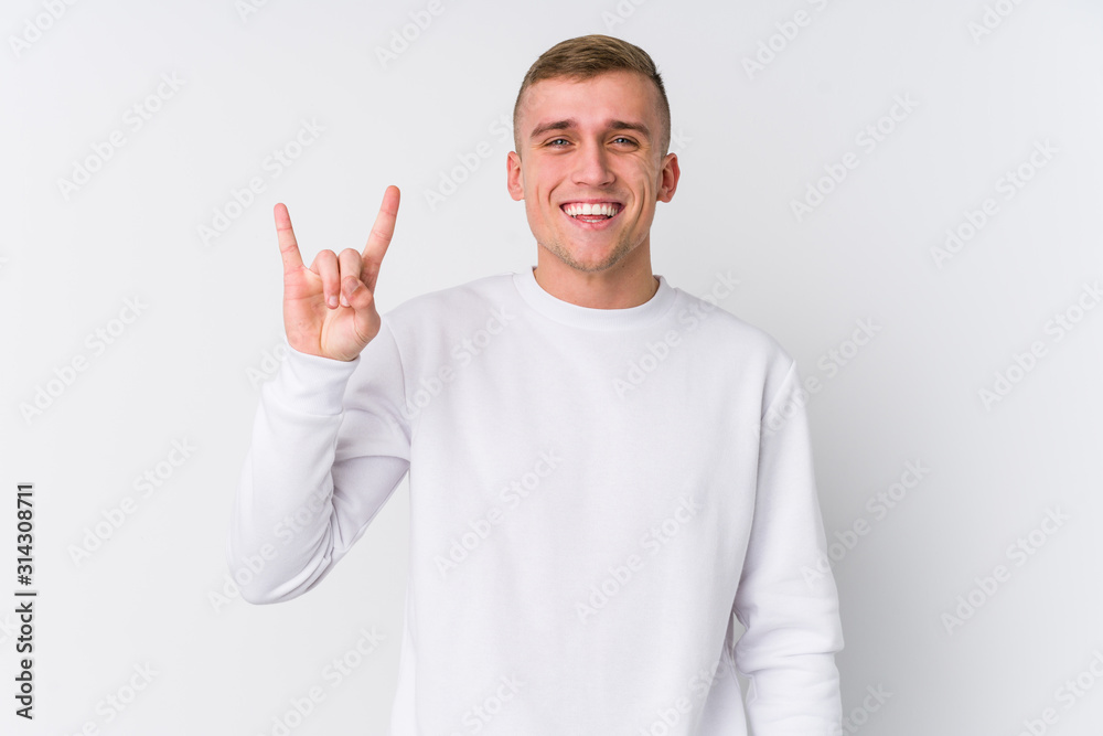 Young caucasian man on white background showing a horns gesture as a revolution concept. Young caucasian man on white background showing a horns gesture as a revolution concept.