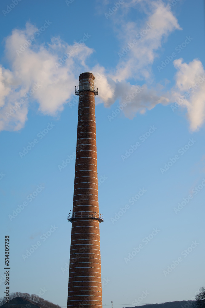 Brick tall pipe with thick smoke closeup. Environmental pollution, ecology. Vertical orientation