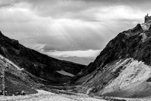 Black and white dramatic mountain landscape. The rays of the sun breaking through the clouds.