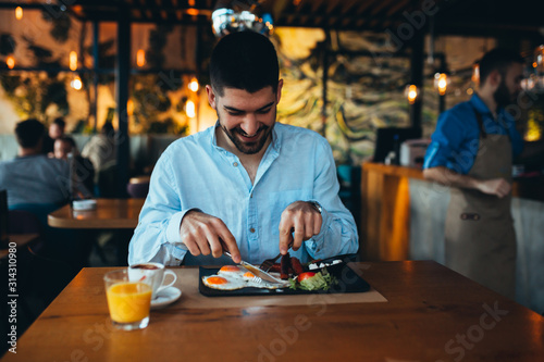 young man eating breakfast in restaurant