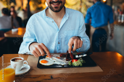 closeup of young man eating breakfast in restaurant