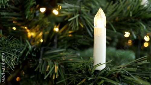 Slow lightning up of fairy lights on Christmas tree with LED candle 4K video