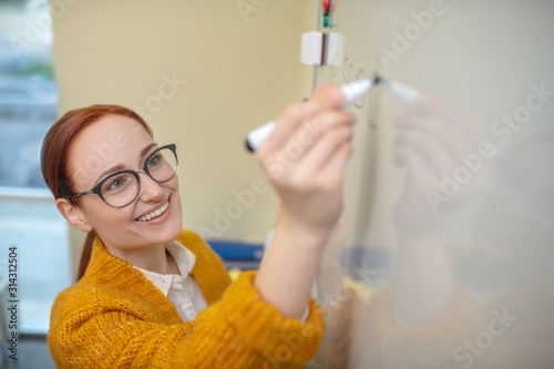 Foto Smiling teacher meticulously writing on the whiteboard