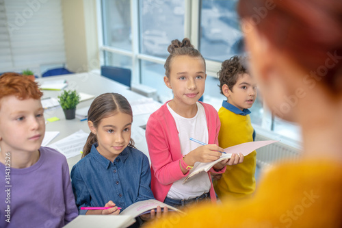 Children listening to the teacher and taking notes photo