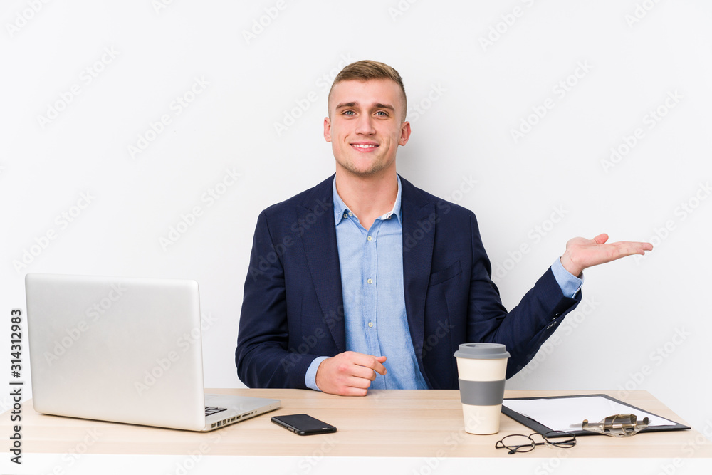 Young business man with a laptop showing a copy space on a palm and holding another hand on waist. Young business man with a laptop showing a copy space on a palm and holding another hand on waist.