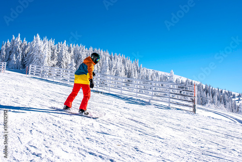 Snowboarder riding snowboard in mountain ski resort with beautiful winter landscape in the background