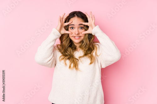 Young curvy woman posing in a pink background isolated keeping eyes opened to find a success opportunity. © Asier