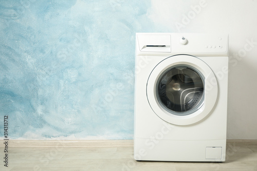 Modern washing machine against blue background, space for text