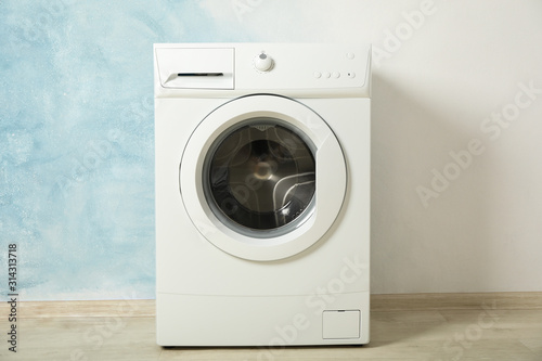 Modern washing machine against blue background, space for text