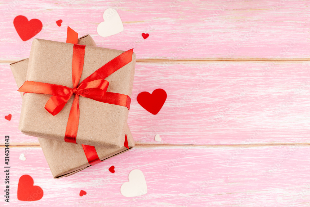 Valentine's Background with Two Gift Boxes with Red Ribbon Bow and Confetti Paper Hearts on Pink Wooden Background. Love, Romance, Happy Valentines Day Concept. Top View, Copy Space