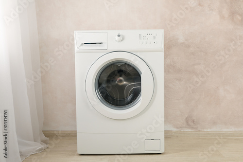 Modern washing machine against brown wall, space for text