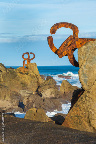 Vertical view of two sculptures of the Peine del Viento, with rocks, a sunny winter day. San Sebastian, Spain, on December 24, 2019.