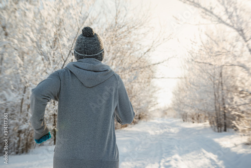 Running sport woman. Female runner jogging in cold winter forest wearing warm sporty running clothing and gloves.