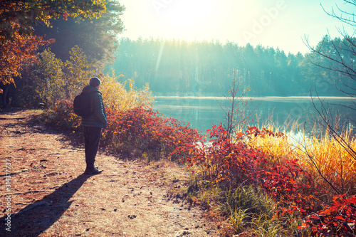 Εκτύπωση καμβά Man tourist stands on a picturesque lakeshore in the autumn morning and looking