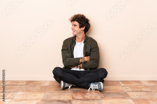 Young caucasian man sitting on the floor in lateral position