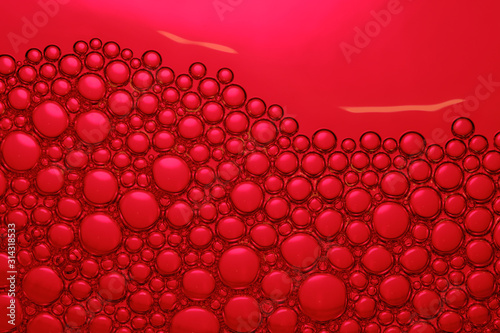 Abstract red background with soap bubbles in the water. Foam in high magnification. Close-up. Macro.