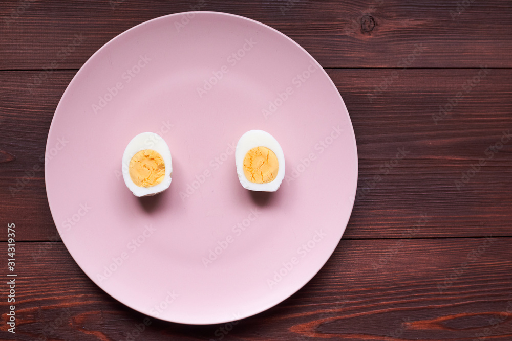 Boiled chicken egg cut into two halves on a pink plate. Boiled chicken egg cut into two halves on a pink plate.