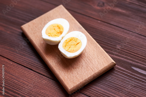Boiled chicken egg cut into two halves on a wooden background.