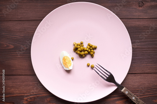 Peas and chicken egg on a plate. Poor, poor food. The concept of diet, malnutrition.