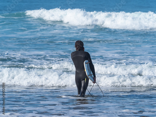 Man with a surfboard entering the sea, in Sopelana, Basque country.