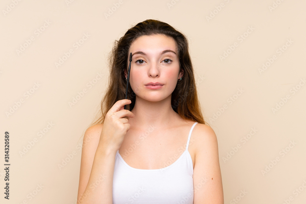 Young brunette girl applying mascara with cosmetic rush over isolated background Young brunette girl applying mascara with cosmetic rush over isolated background