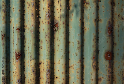 Fence and wall made of currugated iron - structure and surface of material us rusty and corroded. Old, aged, faded and tarnished material.  photo