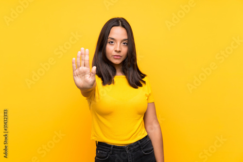 Young brunette girl over isolated background making stop gesture