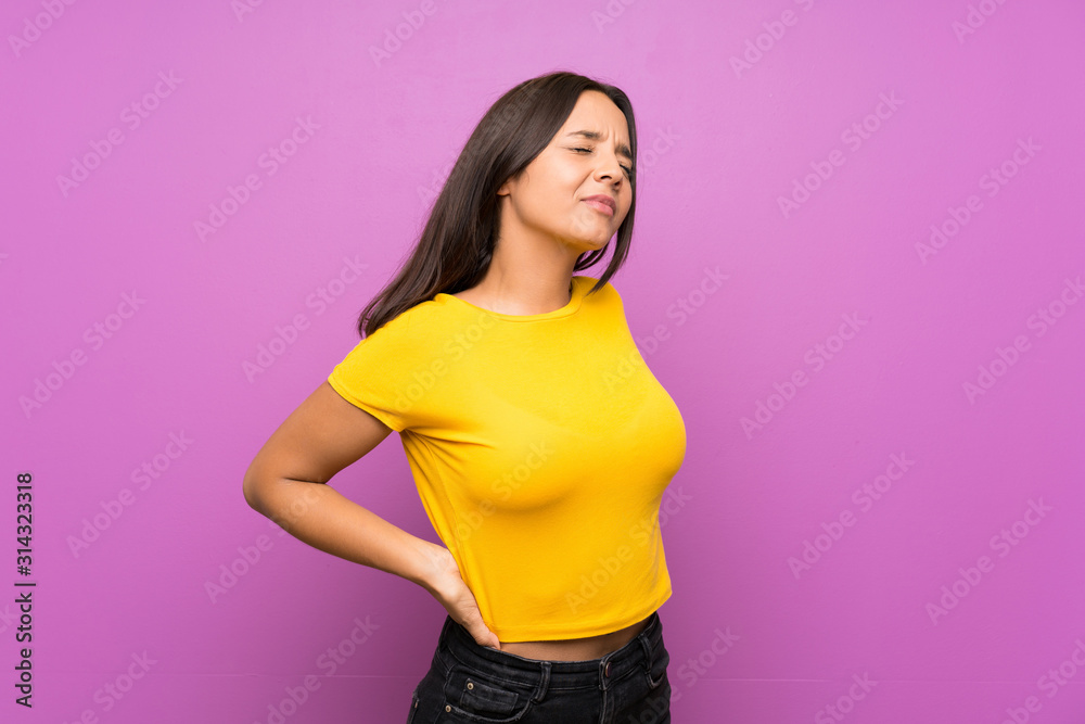 Young brunette girl over isolated background suffering from backache for having made an effort Young brunette girl over isolated background suffering from backache for having made an effort