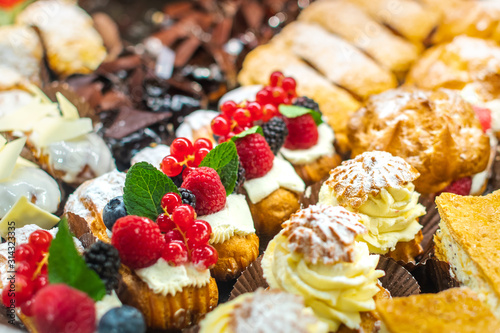 Pastry shop with variety of donuts, muffins, creme brulee, cakes with fruits and berries