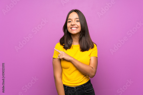 Young brunette girl over isolated background pointing to the side to present a product
