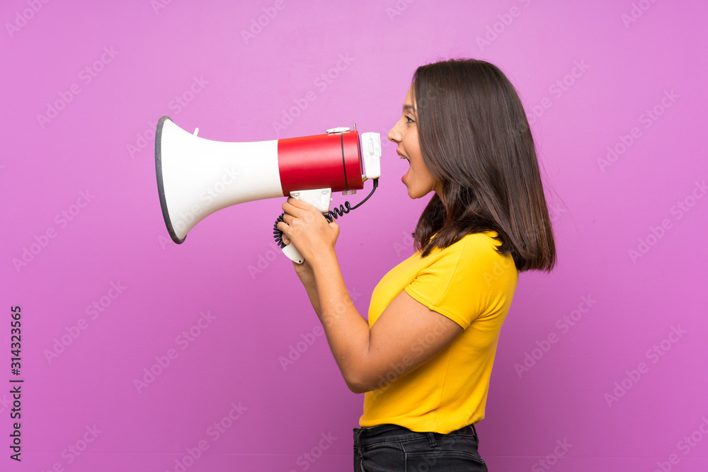 Young brunette girl over isolated background shouting through a megaphone Young brunette girl over isolated background shouting through a megaphone