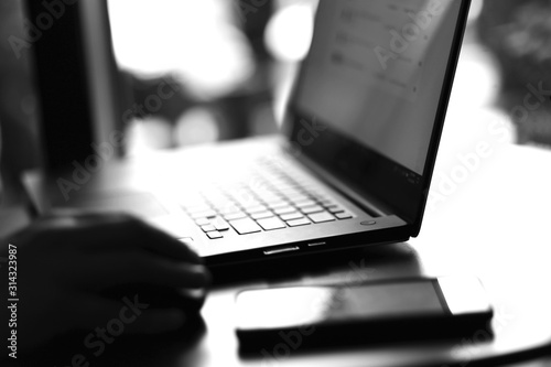 Close up view of laptop and mobile phone with freelancer working on it black and white