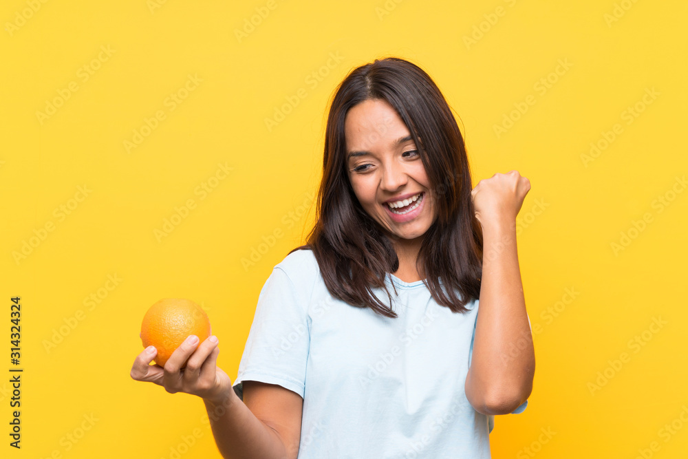 Young brunette woman holding an orange celebrating a victory Young brunette woman holding an orange celebrating a victory