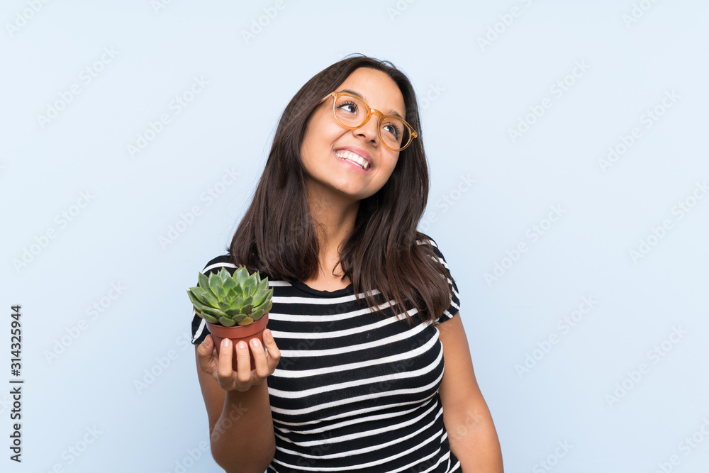 Young brunette woman holding a plant looking up while smiling Young brunette woman holding a plant looking up while smiling
