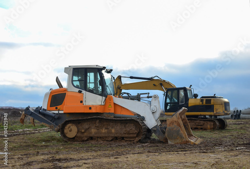 Crawler Loader and excavator at construction site. Land clearing, grading, pool excavation, utility trenching and foundation digging. Crawler tractor,  dozer, earth-moving equipment. © MaxSafaniuk