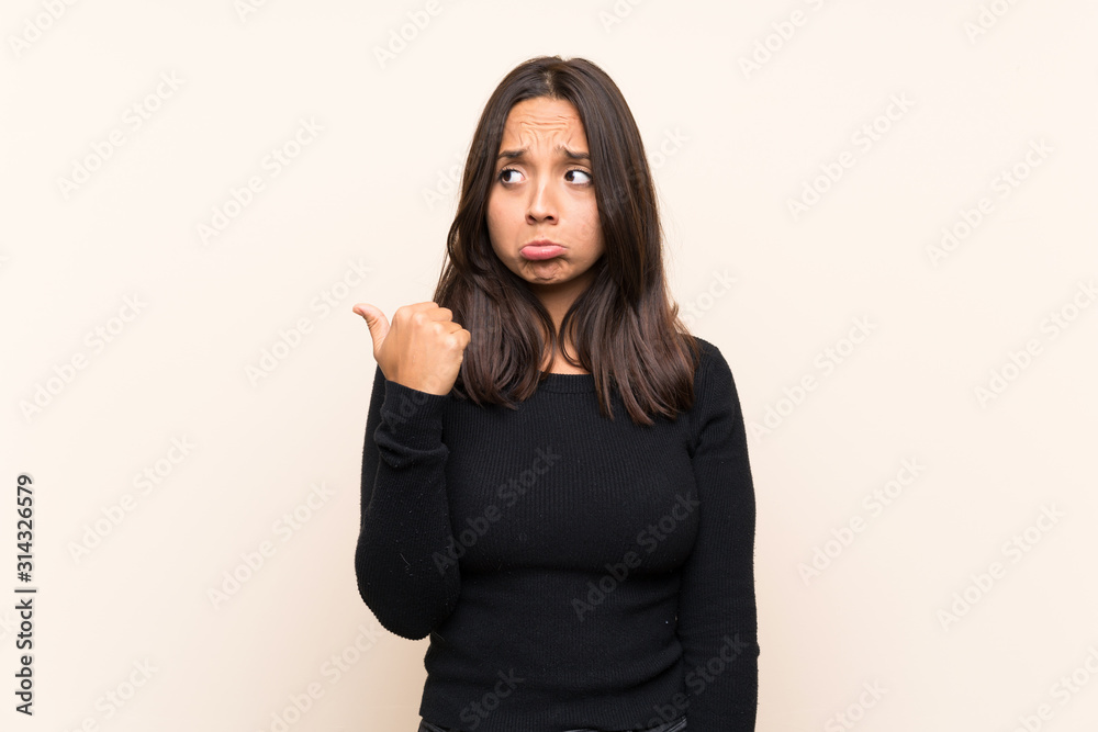 Young brunette woman with white sweater over isolated background unhappy and pointing to the side Young brunette woman with white sweater over isolated background unhappy and pointing to the side