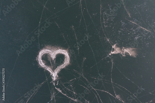 An ice heart drawn by skates on the surface of a frozen lake. The view from the top.