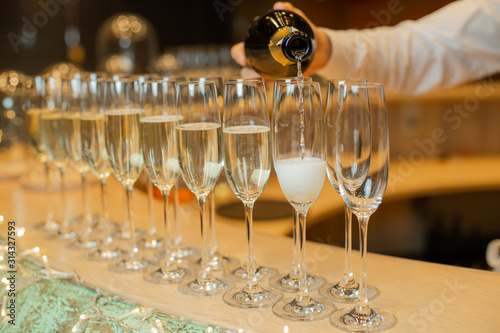 Clous up sparkling champagne bottle filling goblets with wine.