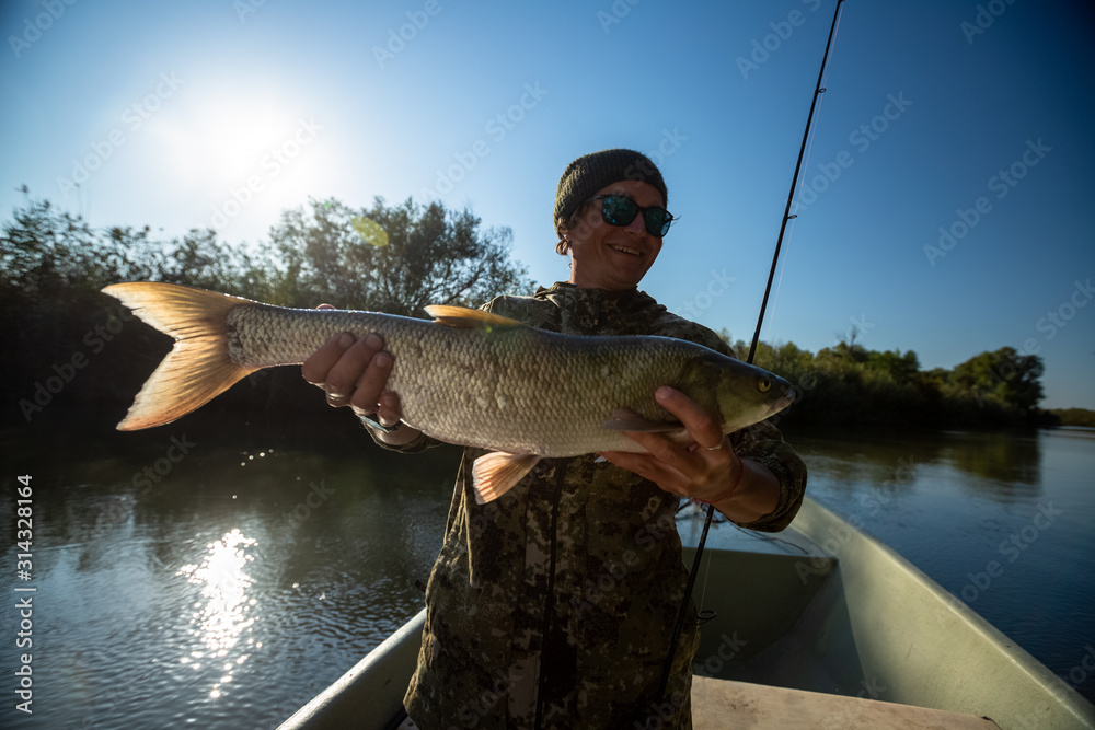Happy fisherman holds the Asp fish and smiles Happy fisherman holds the Asp fish and smiles