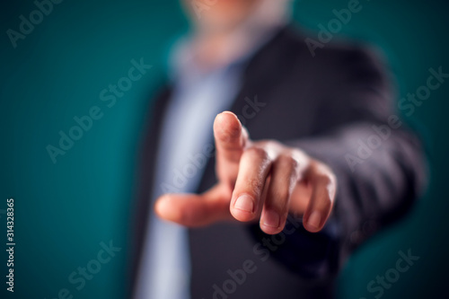 Businessman in suit pressing virtual button or pointing at something