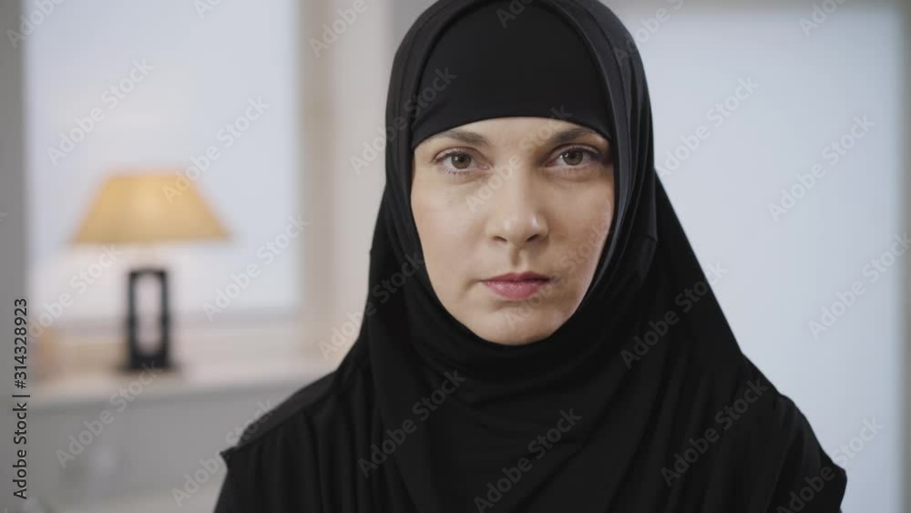 Portrait of beautiful Muslim woman looking at camera and gesturing no by shaking head. Portrait of eastern lady with brown eyes in black hijab. Traditional dress, Muslim culture. Portrait of beautiful Muslim woman looking at camera and gesturing no by shaking head. Portrait of eastern lady with brown eyes in black hijab. Traditional dress, Muslim culture.