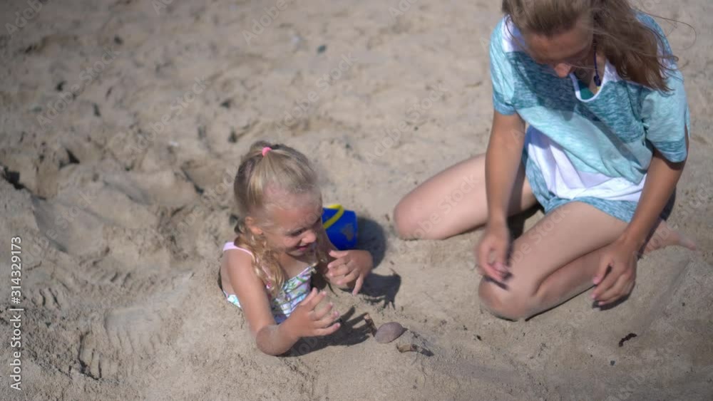 daughter girl buried in sand and her mom playing with sand daughter girl buried in sand and her mom playing with sand