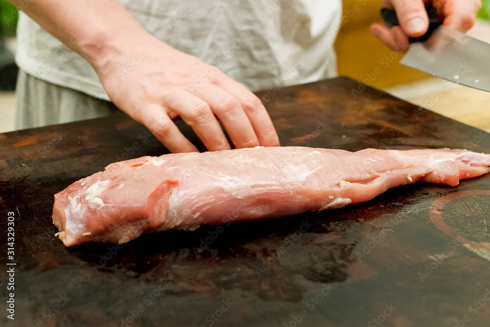 Cutting piece of pork meat on the table. Raw pork.