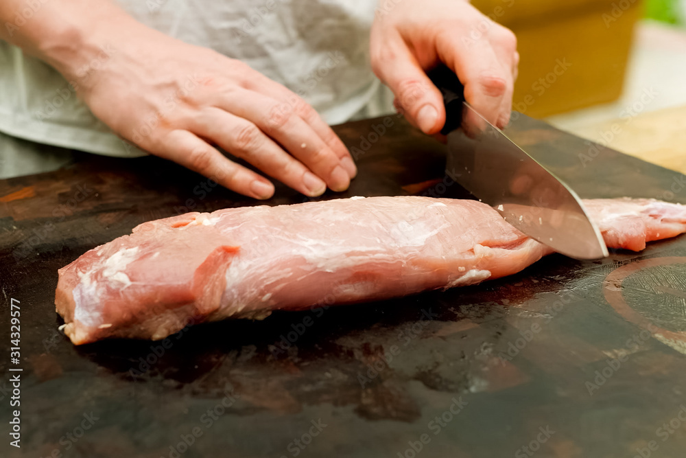 Cutting piece of pork meat on the table. Raw pork.