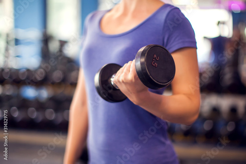 Woman training with dumbbells in the gym. People, fitness and health concept